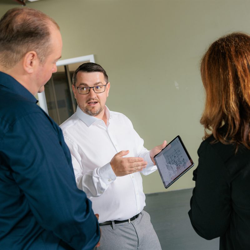Martin Höschler zeigt zwei Gesprächspartnern einen Grundriss auf dem Tablet